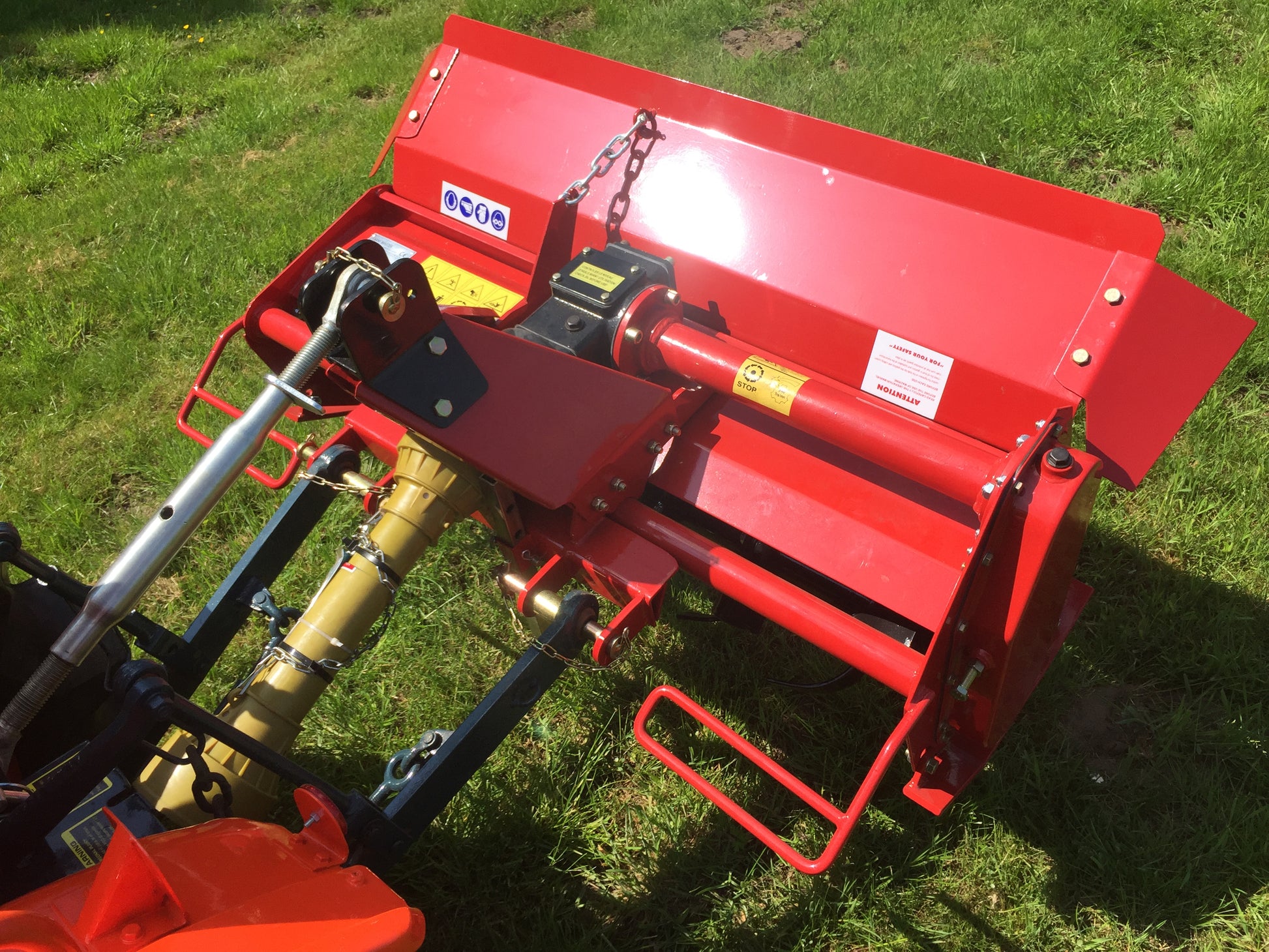 Red tractor tiller on a grassy field