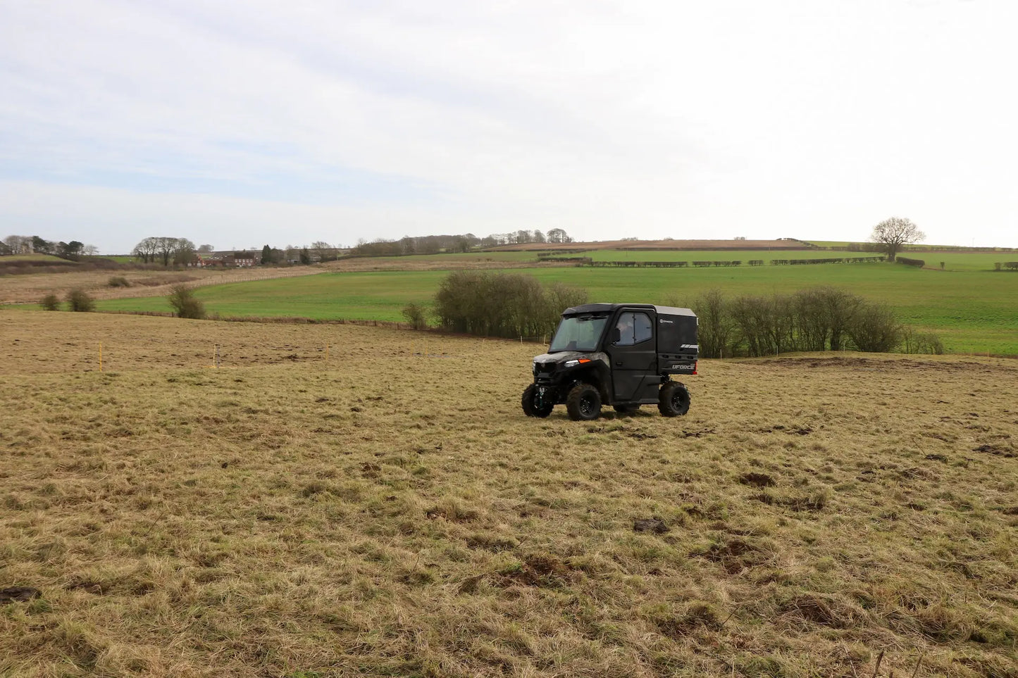 CFMOTO UFORCE 600 Highland UTV in a field with rolling hills and trees in the background