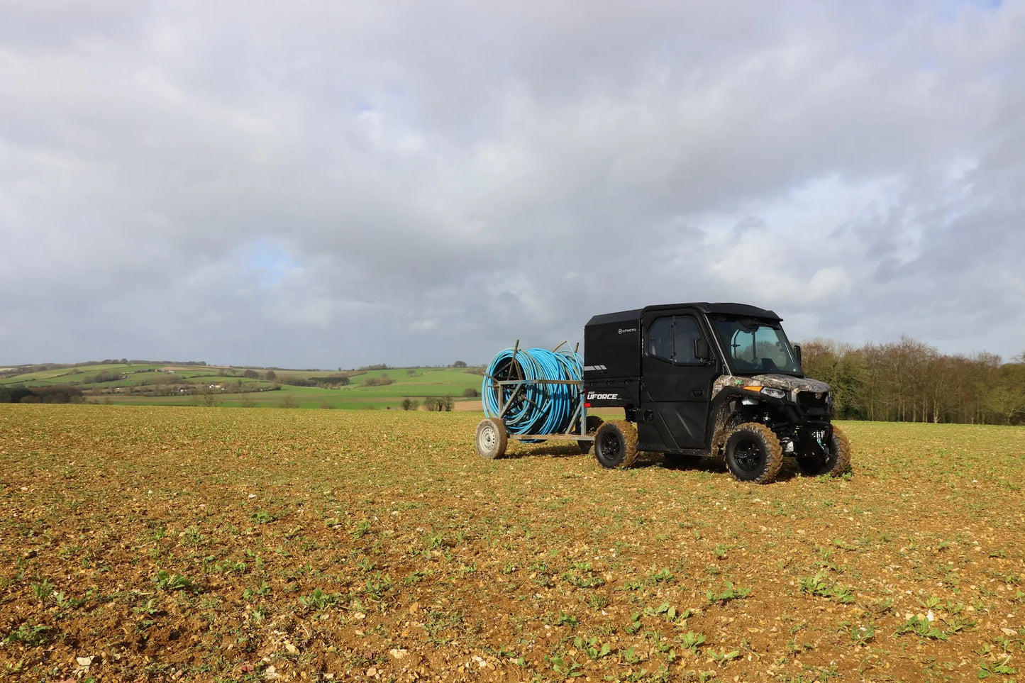 CFMOTO UFORCE 600 Highland UTV with a hose reel in a field under a cloudy sky