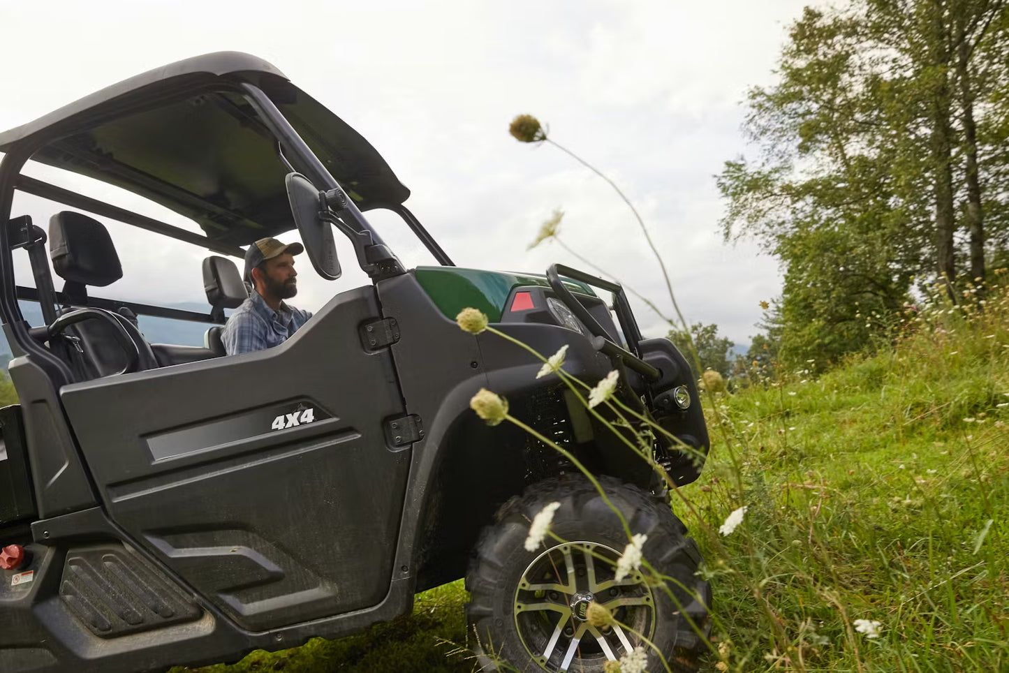 Person inside a Kioti K9 vehicle in a grassy outdoor setting