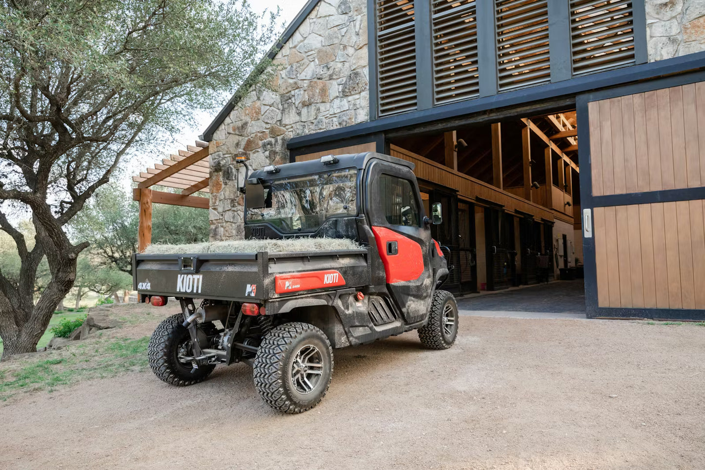 Kioti K9 UTV utility vehicle parked in front of a stone building with wooden doors.