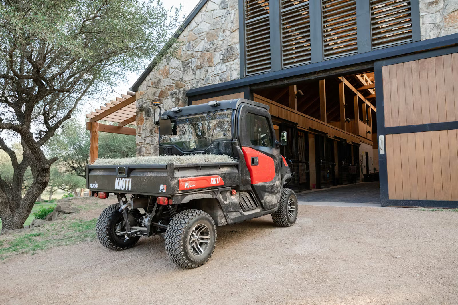 Kioti K9 UTV utility vehicle parked in front of a stone building with wooden doors.