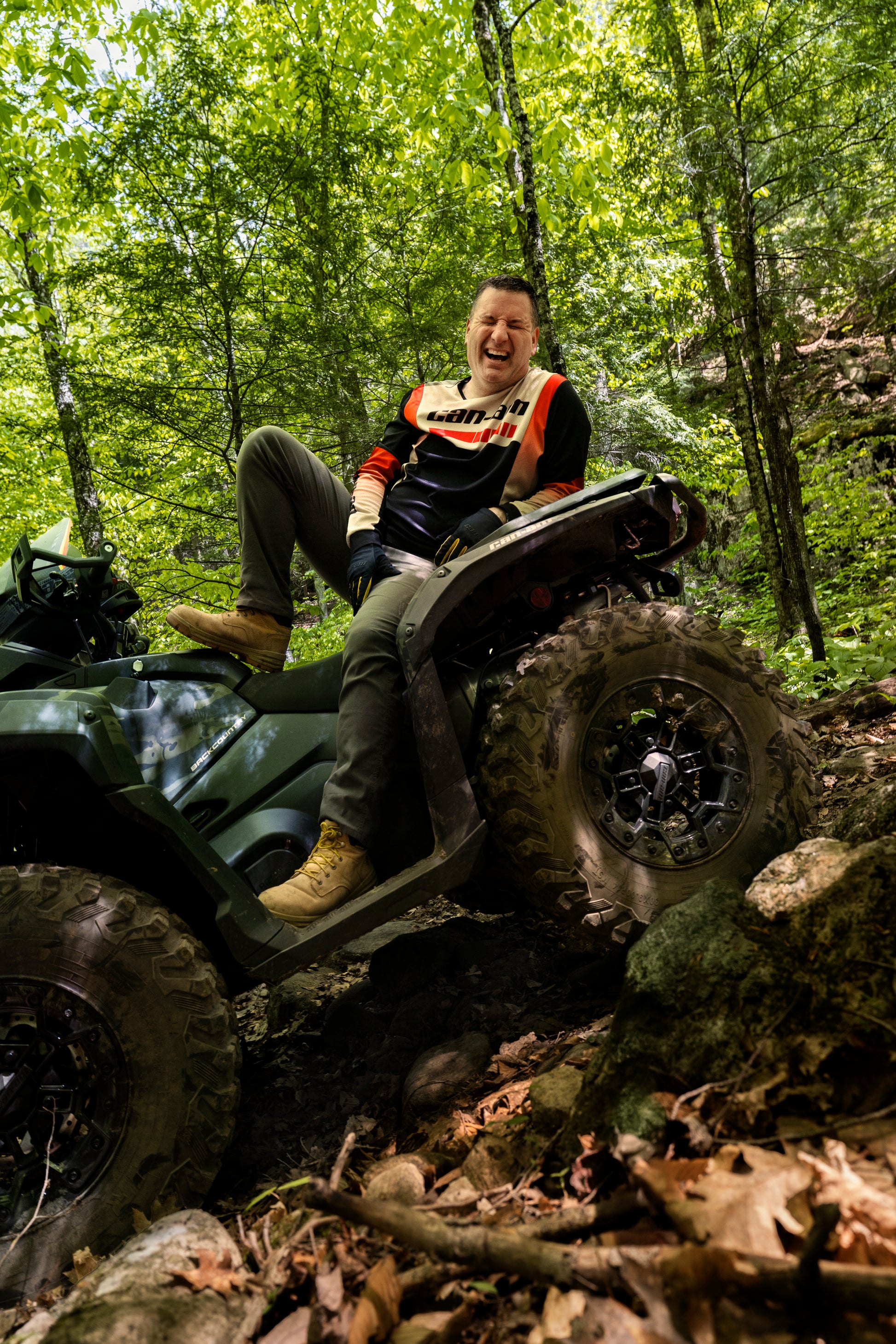 Person riding a Can-Am ATV through a forest