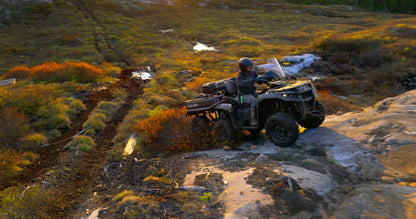 Person riding a Can-Am ATV on a rocky trail in a natural landscape