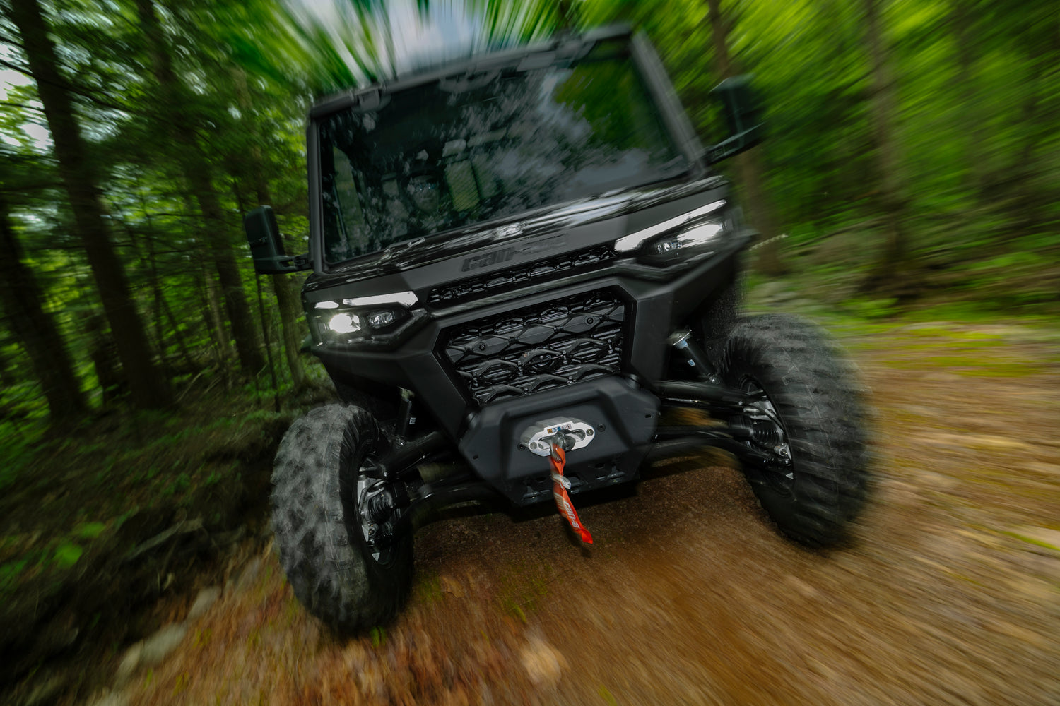 Black Can-Am Traxter UTV driving through a forest