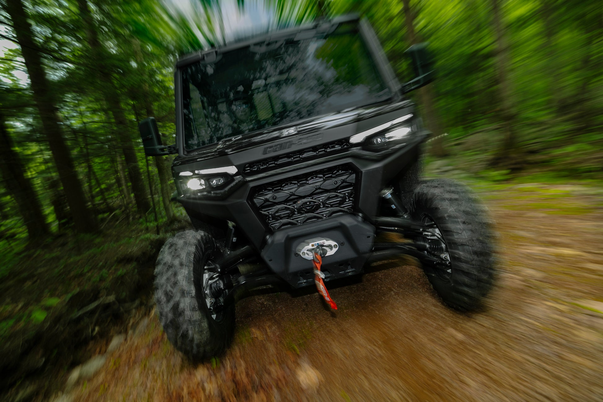 Black Can-Am Traxter UTV driving through a forest