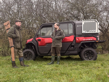 Two men standing next to a red CFMOTO utility vehicle in a grassy area with trees.