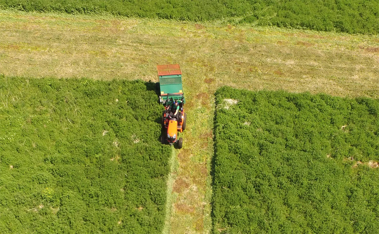 A tractor with a Wessex flail collector is working in a field, viewed from above.