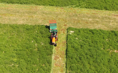 A tractor with a Wessex flail collector is working in a field, viewed from above.