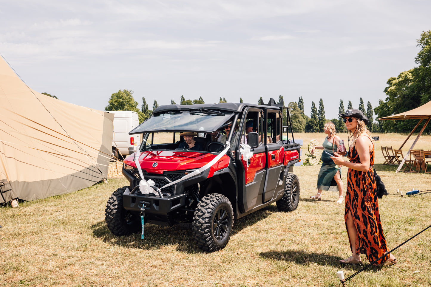 Red CFMOTO UFORCE U10 Pro XL vehicle parked on grass at a wedding