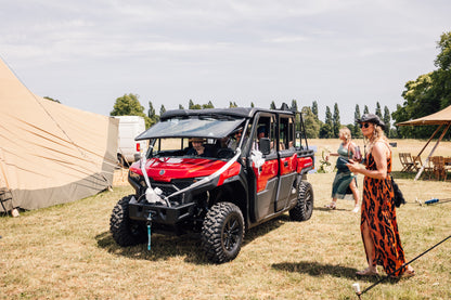 Red CFMOTO UFORCE U10 Pro XL vehicle parked on grass at a wedding