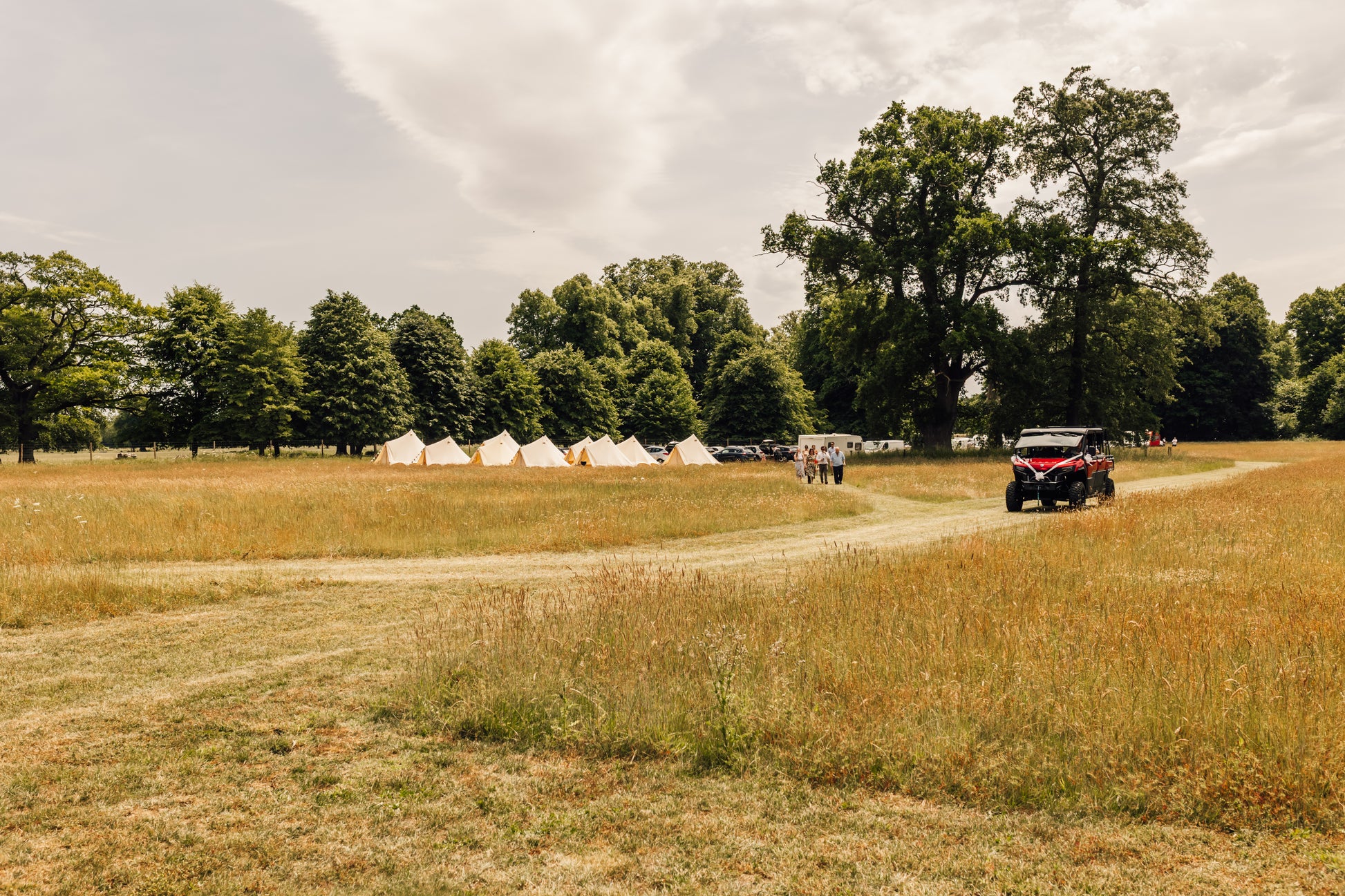 Tents set up in a field with a CFMOTO vehicle on a dirt path