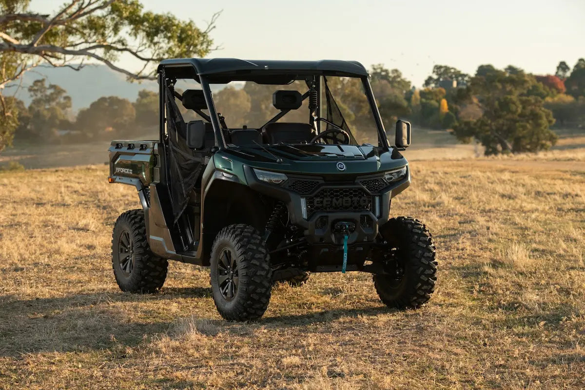 CFMOTO U10 Pro Utility vehicle in a field with trees and mountains in the background