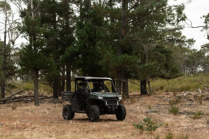 CFMOTO UTV in a forested area with trees and dry grass.
