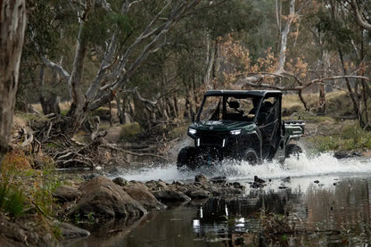 CFMOTO All-terrain vehicle crossing a shallow stream in a forested area