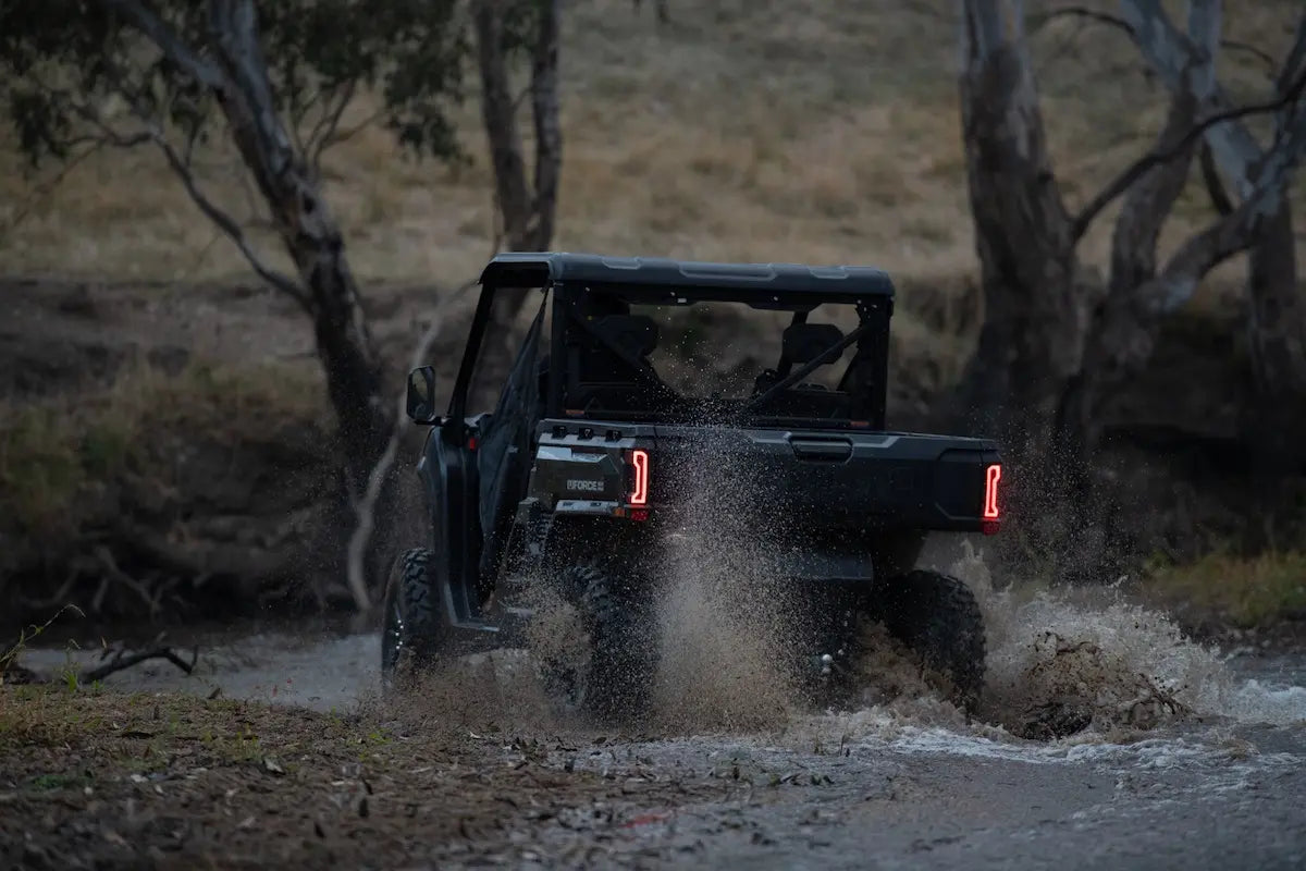 CFMOTO U10 Pro UTV Off-road vehicle driving through a muddy puddle in a natural setting with trees.