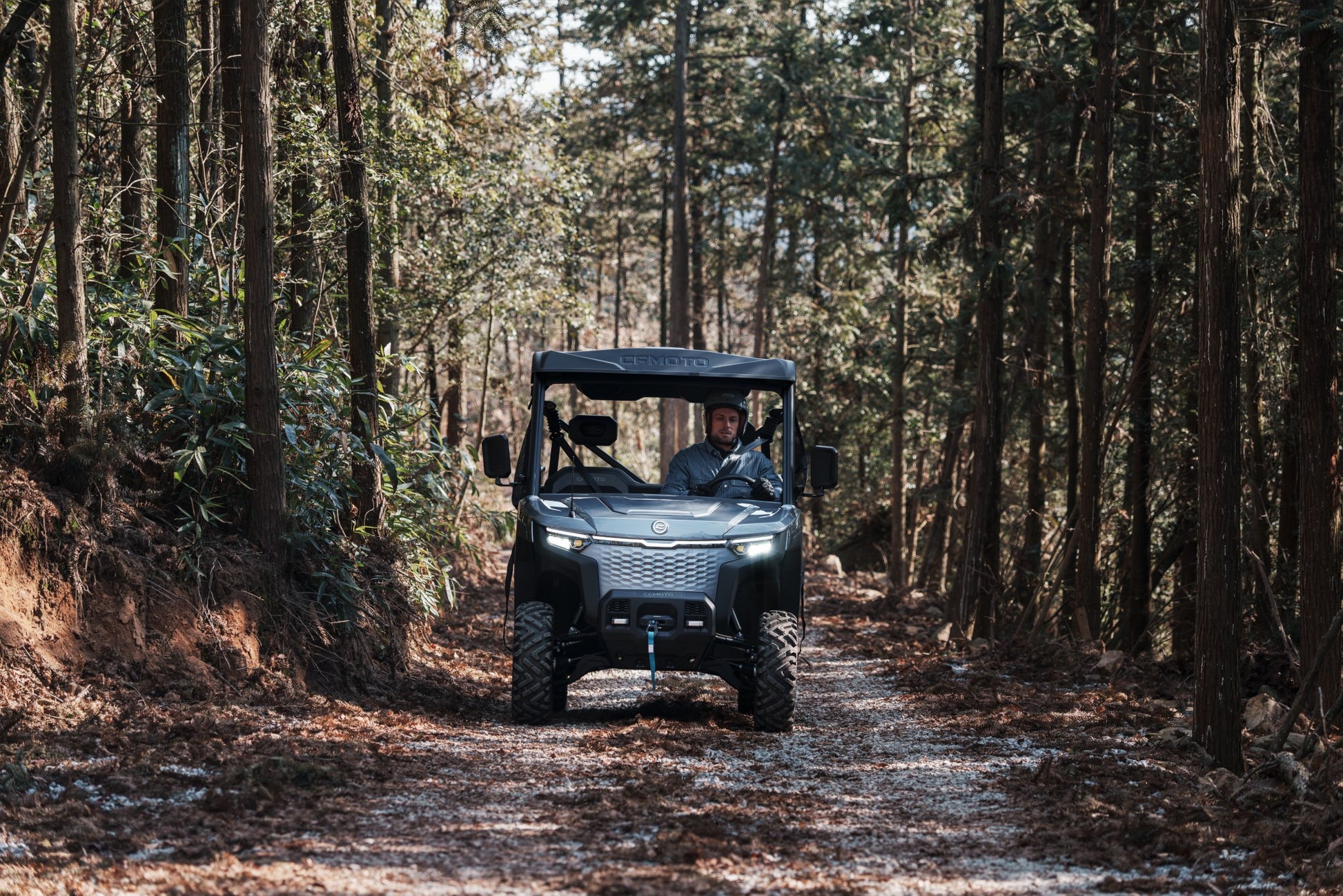Person driving a CFMOTO U6EV Electric UTV through a forest