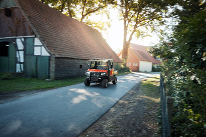 Kioti K9 off-road vehicle on a rural road with a barn and trees in the background