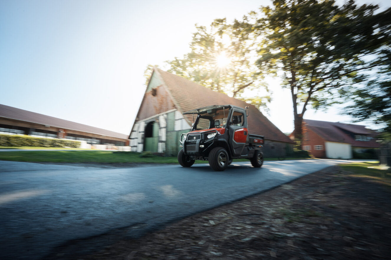 Kioti K9 Utility vehicle on a road with a barn and trees in the background