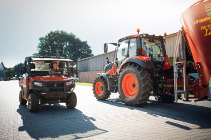 Kioti K9 Red utility vehicle towing a large red tractor with a trailer on a paved area.