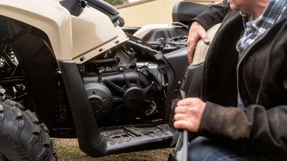 Person working on the engine of a Can-Am four-wheeler vehicle