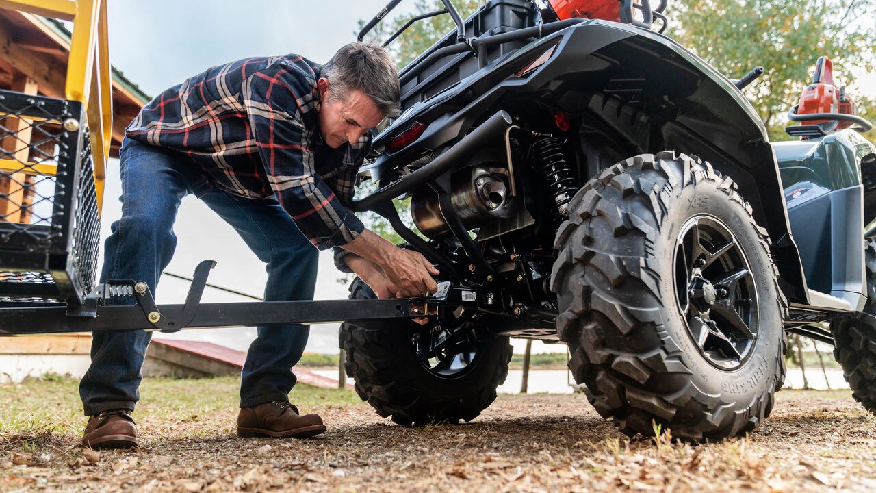 Man working on a Can-Am ATV in a rural setting
