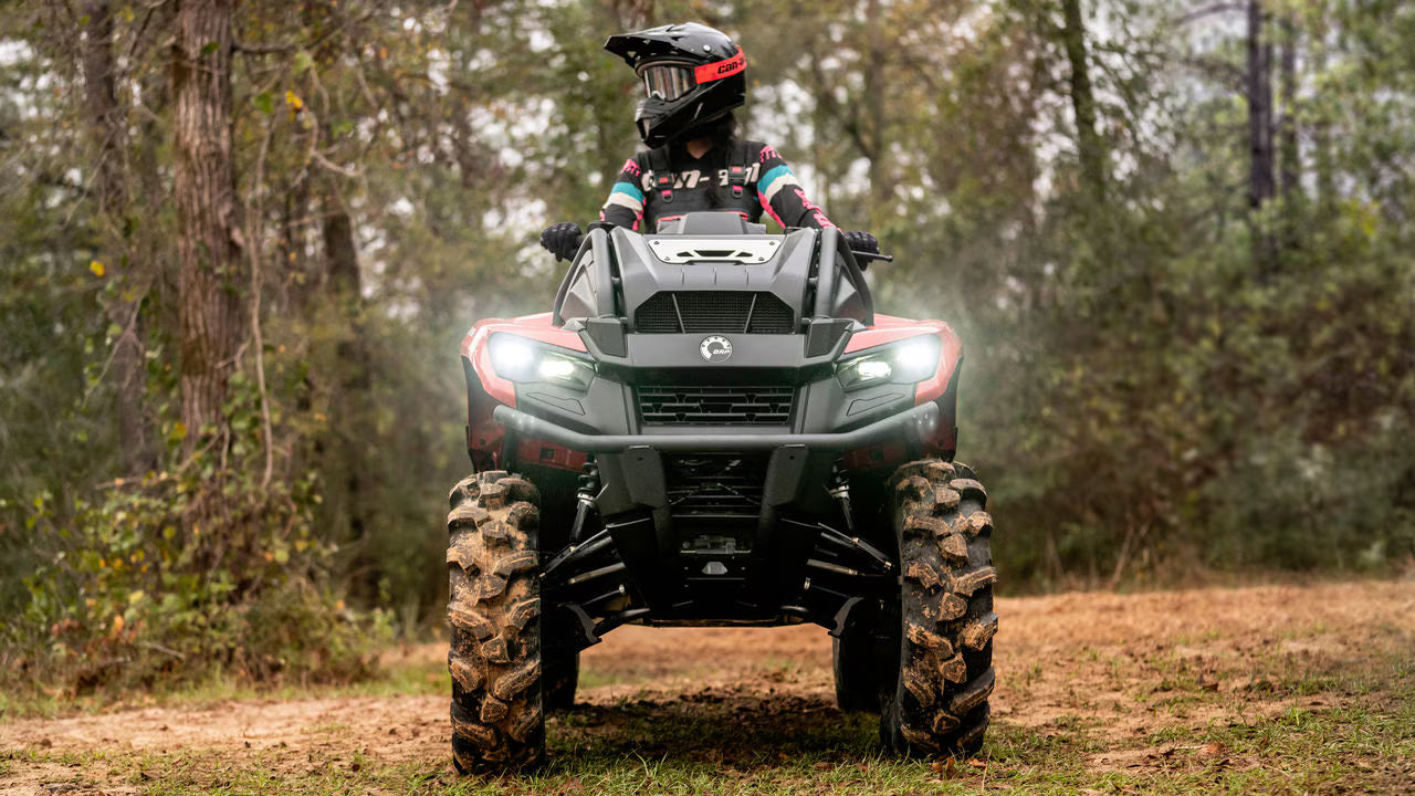 Person riding a Can-Am ATV in a forested area