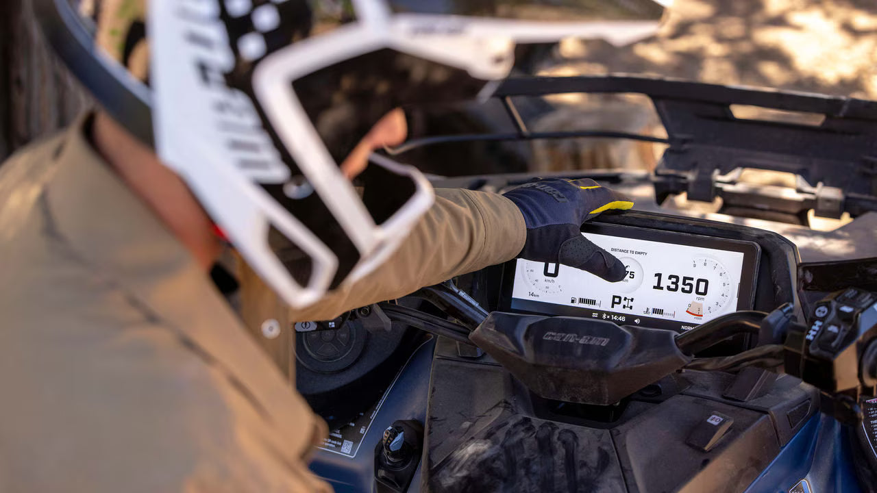Person operating a Can-Am ATV with a digital display showing speed and other metrics.
