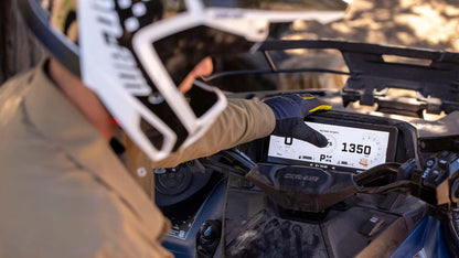 Person operating a Can-Am ATV with a digital display showing speed and other metrics.