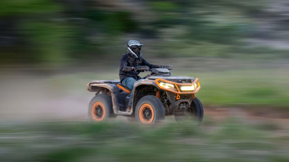 Person riding a Can-Am ATV on a trail with blurred background