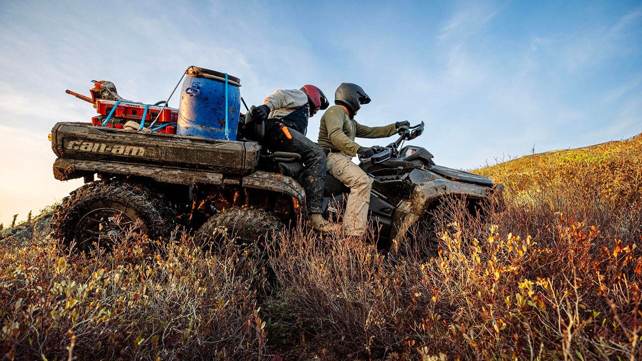 Person on a Can-Am Outlander 6x6 ATV in a field with a clear sky