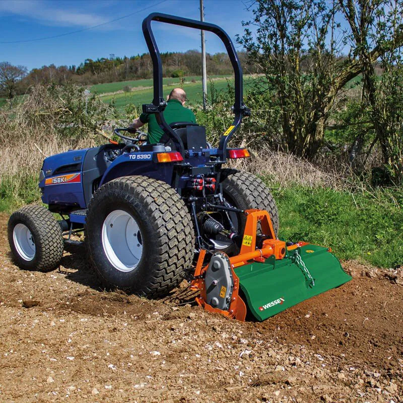 Small blue tractor with a Wessex rotavator attachment in a field