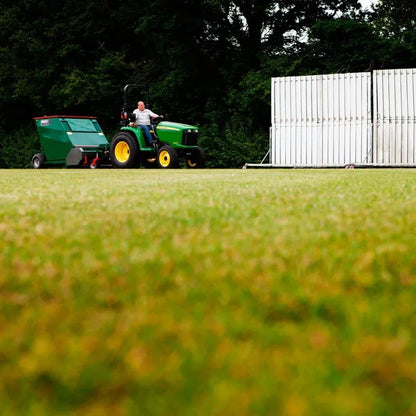 Person driving a green tractor with a Wessex flail collector in the background.