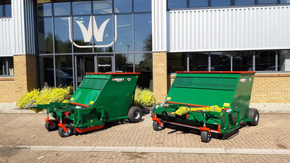 Two green Wessex flail collector parked outside a building with a logo on the glass door.