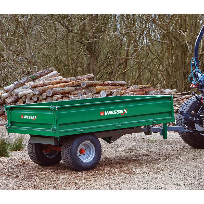 Green Wessex trailer loaded with logs in a wooded area